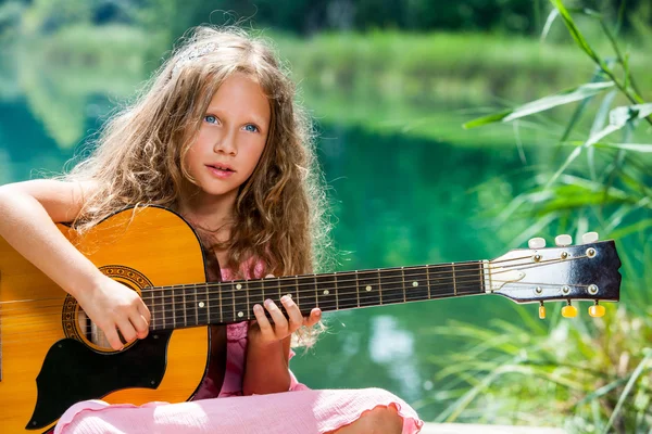 Young guitar student playing at lake. — Stock Photo, Image