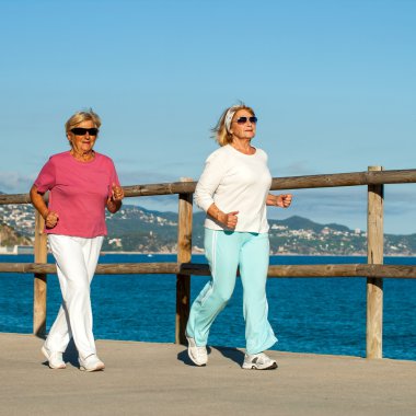 Senior women jogging together outdoors. clipart