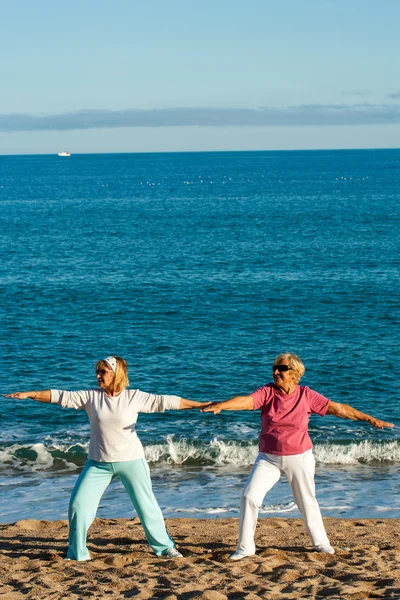 Duas mulheres douradas fazendo ioga na praia . — Fotografia de Stock