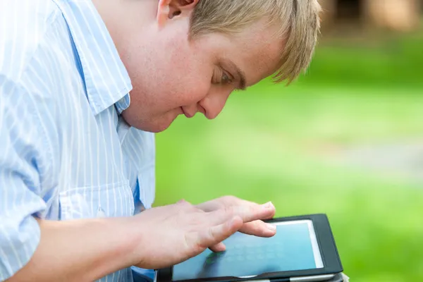 Kid with down syndrome playing on tablet. — Stock Photo, Image