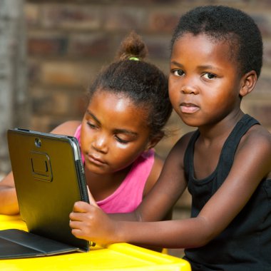 tablet ile masada oturan iki Afrikalı kız.
