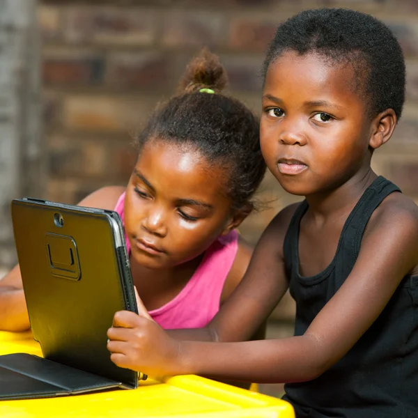 Two african girls sitting at table with tablet. — Stock Photo, Image