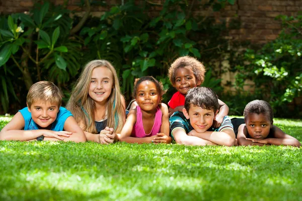 Diverse group of kids together in garden. Royalty Free Stock Images