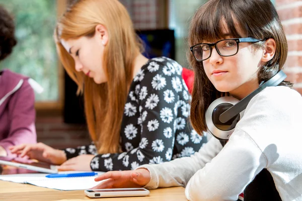 Cute girl with friends at schoolwork table. — Stock Photo, Image