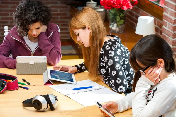 Três estudantes trabalhando em dispositivos digitais . — Fotografia de Stock