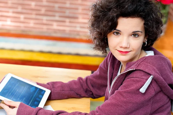 Roztomilá dívka sedí u stolu s počítačem tablet. — Stock fotografie