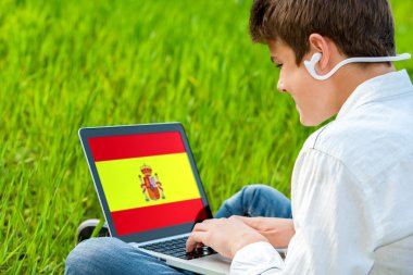 Teen student doing spanish course on laptop. clipart