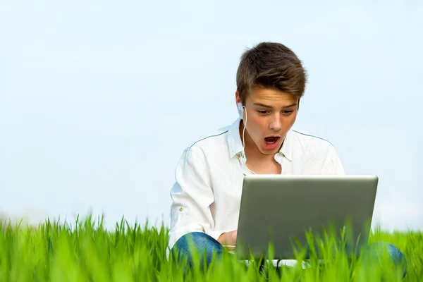Здивований хлопчик з ноутбуком на відкритому повітрі . — стокове фото
