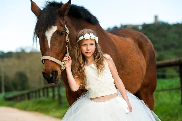 Милая девушка, стоящая рядом с лошадью . — стоковое фото
