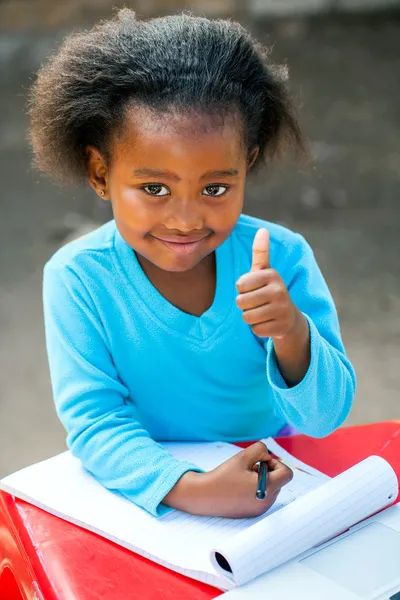 Африканський студент робить великі пальці на стіл. — стокове фото