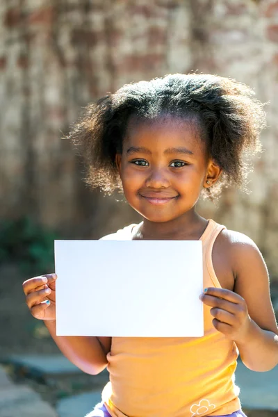 Χαριτωμένο αφρικανικής κορίτσι εκμετάλλευση λευκό κενό κάρτα. — Φωτογραφία Αρχείου