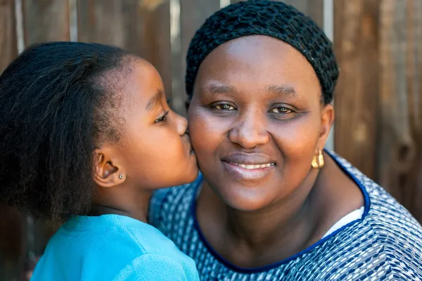 Menina africana beijando mãe na bochecha . — Fotografia de Stock