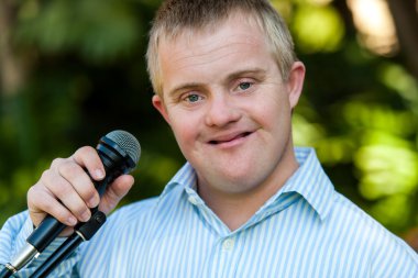 Mikrofonu tutan synfrome aşağı olan çocuk