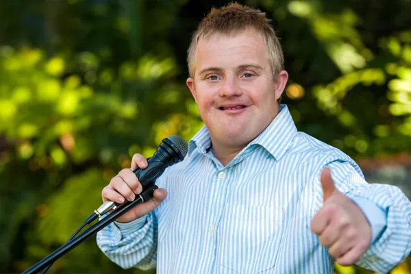 Handicapped boy with microphone doing thumbs up. — Stock Photo, Image