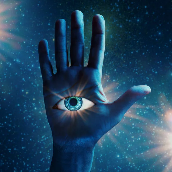 Conceptual abstract human hand with all seeing eye in palm. Mystic symbol in blue hand against cosmic background.