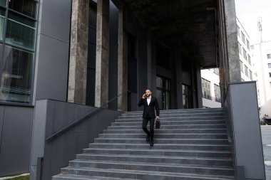 Bir iş adamı merdivenlerden inerken cep telefonuyla konuşur.
