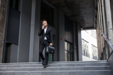 Ofis binasının önünde merdivenlerden inen başarılı genç işadamı.