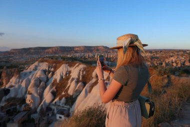 Kapadokya 'daki güzel manzaranın fotoğrafını çeken bir kadın mobil kamerayla, rüya gibi seyahat konseptiyle.