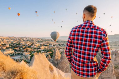 Kapadokya, Türkiye 'de sabahları uçan balonların güzel manzarasının tadını çıkaran bir adam.