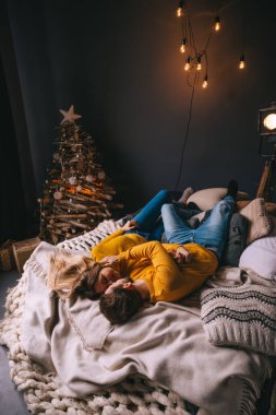 Mutlu çift yatakta uzanıyor ve evde birlikte dinleniyorlar. Romantik çift birbirine bakıyor ve kış tatili boyunca dinleniyor..