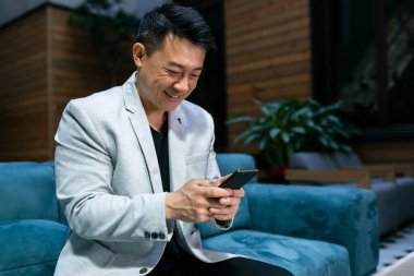 Lüks takım elbiseli genç bir erkek işadamının portresi. Tatil sırasında telefonda konuşuyor. Ofiste bir iş görüşmesi için hazırlanırken cep telefonunu kullanan zeki bir adam.