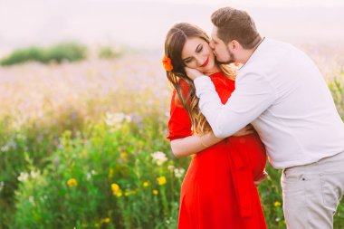 Genç, mutlu, romantik, hamile çift parkta öpüşüyor, sarılıyor, karnına dokunuyor. Gelecekteki anne ve baba, aile. Annelik.