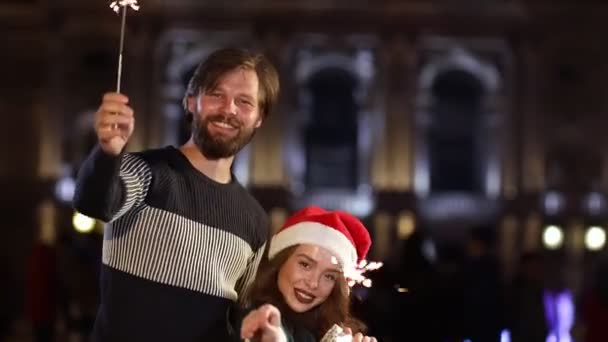 这对快乐的夫妇抱着火花 心情愉快地站在外面 戴着圣诞礼帽的快乐男女庆祝新年 — 图库视频影像