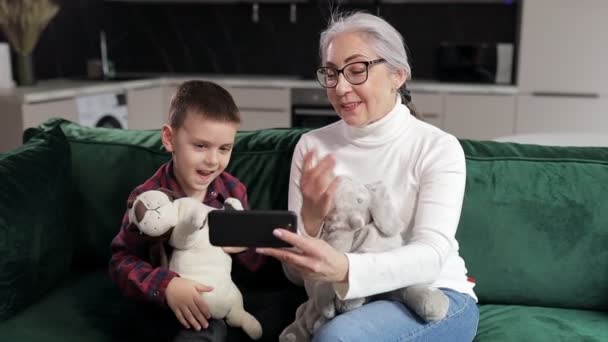 Grandmother Grandson Sitting Couch Woman Shows Boy Cartoons Mobile Phone — 图库视频影像