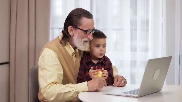 Moderne Grootvader Met Zijn Kleinzoon Zit Met Laptop Aan Tafel — Stockvideo