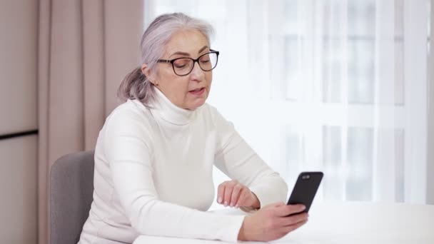 Starsza Kobieta Siedzi Kuchni Używa Aplikacji Wideo Smartfonie Wita Dorosłych — Wideo stockowe