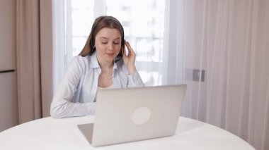 Kablosuz kulaklıklı, arkadaş canlısı iş kadını iş arkadaşlarıyla internet üzerinden bir video görüşmesi başlatıyor.