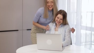 Bir kadın masaya oturur ve dizüstü bilgisayarla çalışır, sevecen bir kız arkadaş su getirir ve bir kıza sarılır, birlikte bilgisayardan bir şey titretirler..