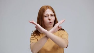 Güzel genç bir kadın inkar eden, reddeden ve elleriyle jest yapan stüdyodaki gri arka planda tek başına duran bir şeye hayır diyor. Olumsuz tepki