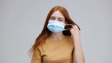 Aşırı neşeli sağlıklı kadın nefes alma özgürlüğünün tıbbi maskesini çıkarıyor. Mutlu bir kız viral enfeksiyonun yayılmasını önlemek için koruyucu ekipmanları çıkartarak iyileşiyor.