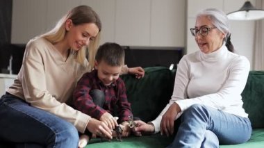 Neşeli sevgi dolu bir aile, anneanne ve küçük çocuk oyuncaklarla oynuyor. Odadaki kanepede oturan hayvanları inceliyorlar. Anne ve oğlu büyükannesini ziyaret ediyor. Aile Günü.