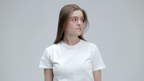 私は知らない Tシャツを着た長いストレートヘアの恥ずかしがり屋の女性は疑問のジェスチャーで彼女の腕を上げ 困惑した無力顔で周りを見回します — ストック動画