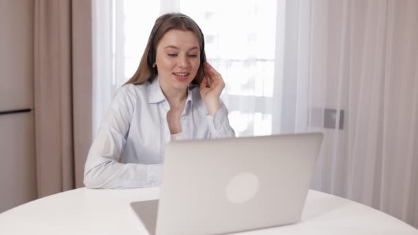 ヘッドフォンの若い魅力的な女性は リモートでノートパソコンのパスジョブインタビューを使用して カウンセラーは ビデオ通話を介してクライアントに距離個人的な心理的なサポートを提供します オフィスコンセプトからの事業 — ストック動画