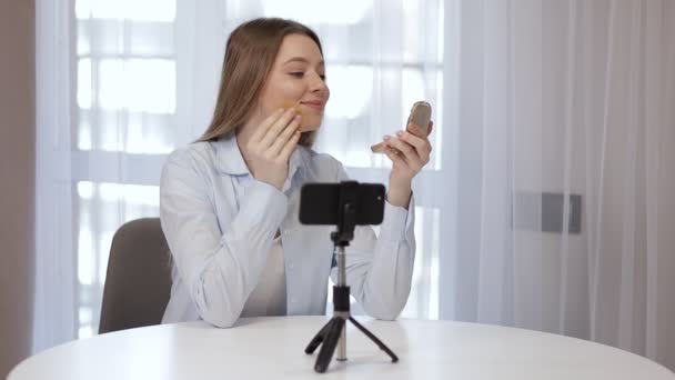 소녀가 인터넷 구독자들 온라인 회의에 얼굴에 광채를 제거하고 삼각대로 핸드폰을 — 비디오