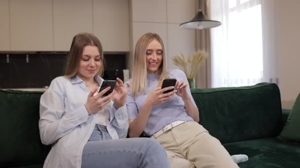 Ευτυχισμένες Νεαρές Γυναίκες Χαλαρώνουν Έναν Άνετο Καναπέ Χρησιμοποιώντας Smartphone Ένα — Αρχείο Βίντεο