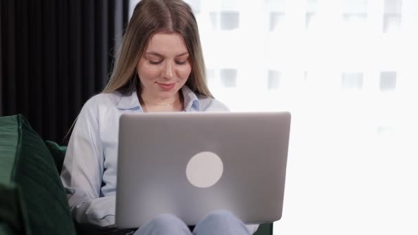 Mujer Joven Sonriente Sentada Sofá Usando Una Computadora Portátil Mirando — Vídeos de Stock