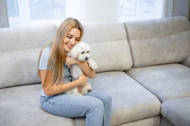 Evde rahatlayan ve köpekle oynayan genç bir kadın var. Evcil hayvan sevgisi kavramı