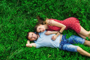 guy and girl hugging each other on green grass and look at camera. top view.