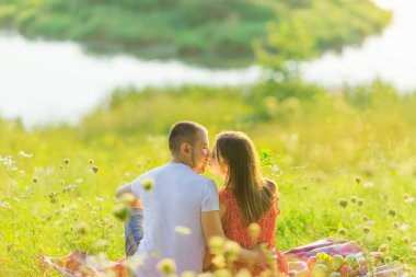 guy and girl sitting on the lake and kissing. back view.