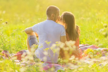 guy and girl kissing. back view. couple in love hugging on a picnic.