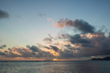 Derin mavi gökyüzü ve güneş ışınlarıyla renkli okyanus plajı gündoğumu.