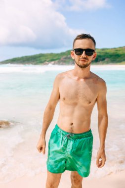 Young man on vacation at the tropical Island La Digue, mid age guy walking on the beach during holiday at tropical beach Seychelles