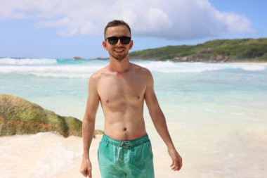 Happy Young man on vacation at the luxury island La Digue Seychelles, beach life palm tree and white sand