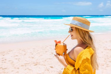 Coconut fresh cocktail, woman drinking tropical drink on sea background