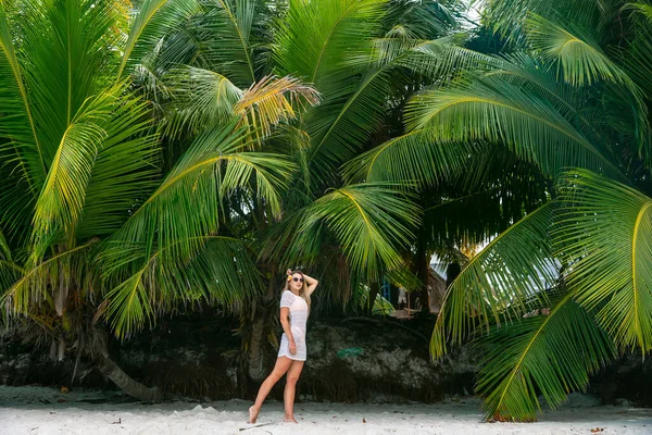 身穿白衣的年轻女子在热带海滩 棕榈树背景 哈瓦伊 头发中的花朵 苗条身材 阳光明媚 享受假期 在岛上旅行 — 图库照片