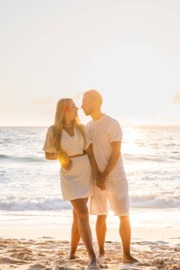 Birbirlerine aşık çiftler plajda gün batımında romantik anlar yaşarlar genç aşıklar yaz tatilinde okyanusun kenarında öpüşürler